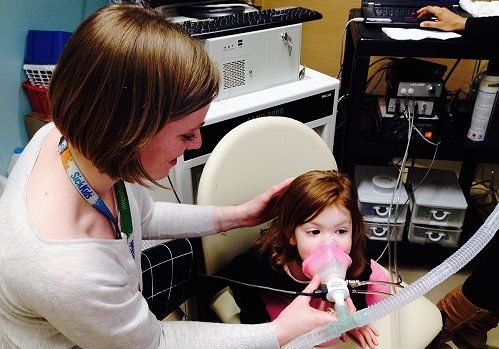 Young girl taking a lung unction test with adult assistance